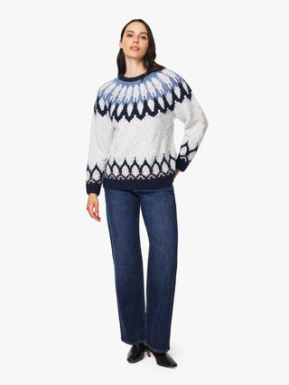 A woman modeling a white Fair Isle knit sweater with navy blue patterns, paired with dark blue jeans and black pointed shoes, against a plain white background.