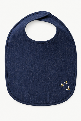 A dark navy blue fabric bib with a small embroidered design of three bumblebees in yellow, white, and black on the lower right corner, shown on a clean off-white background.