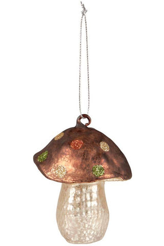 A hanging mushroom ornament with a metallic copper-brown cap decorated with small green and gold glitter spots, and a clear textured glass stem, shown against a plain white background.