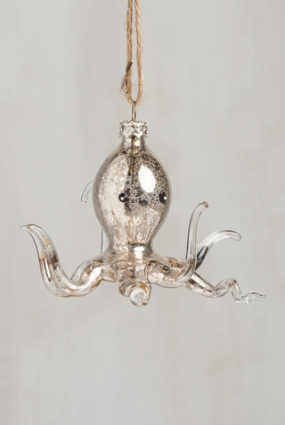 A hanging octopus ornament made from clear glass with a silver-toned mercury-glass finish, small black eyes, and a jute hanging loop at the top, shown against a plain light gray background.