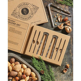 A holiday nutcracker set presented with a nutcracker, nut picker, and shell cracker on a wooden surface, with nuts and spices in the background.